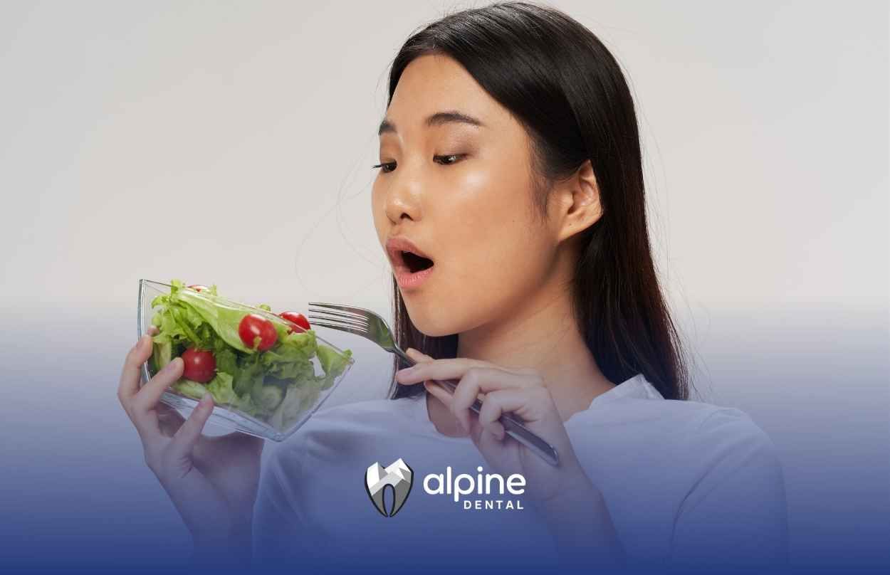 A woman is eating a salad with a fork.
