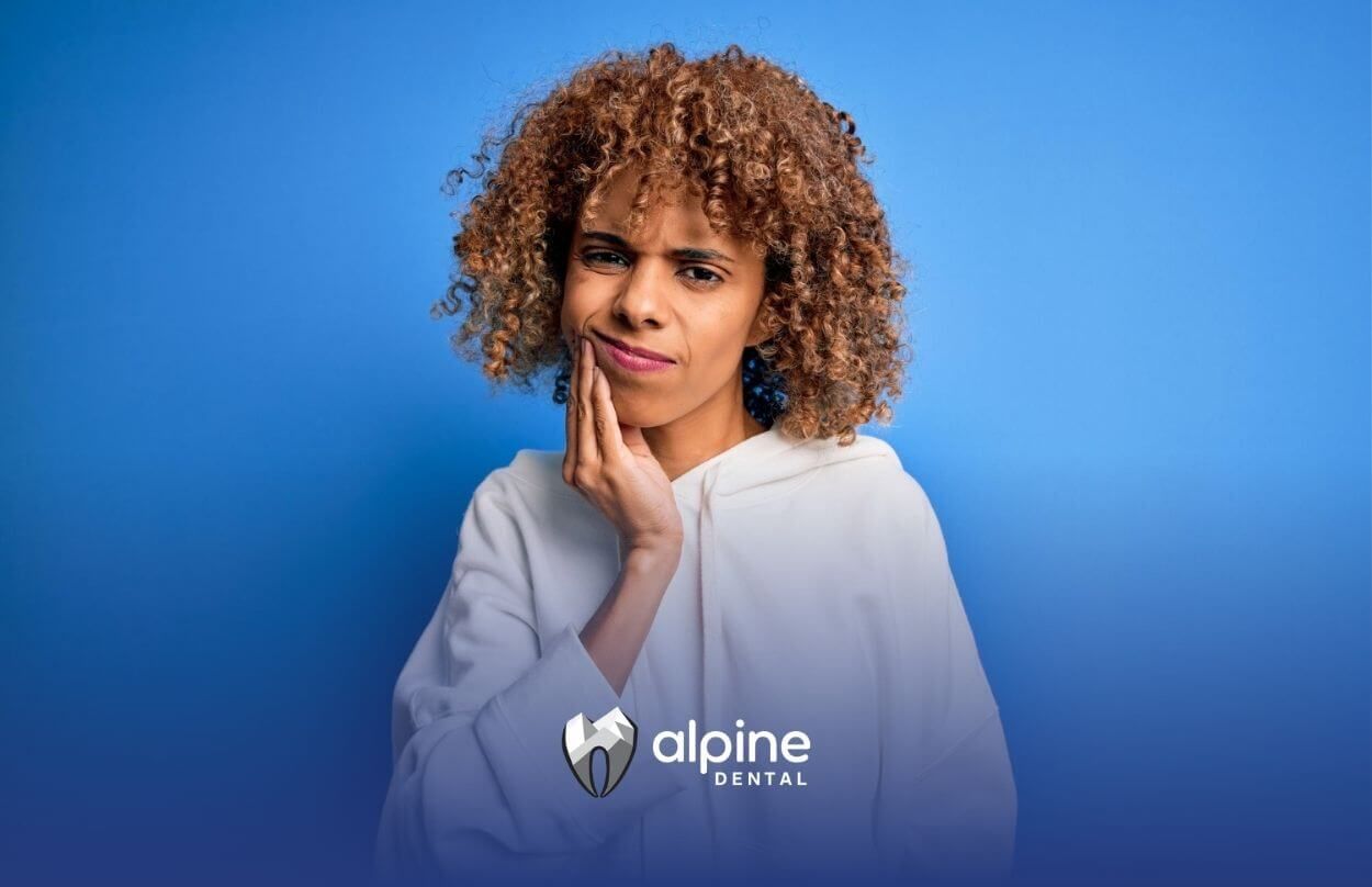 Woman holding her cheek in discomfort, indicating tooth pain.

