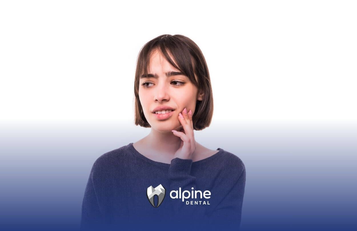 Woman touching her cheek with a pained expression.
