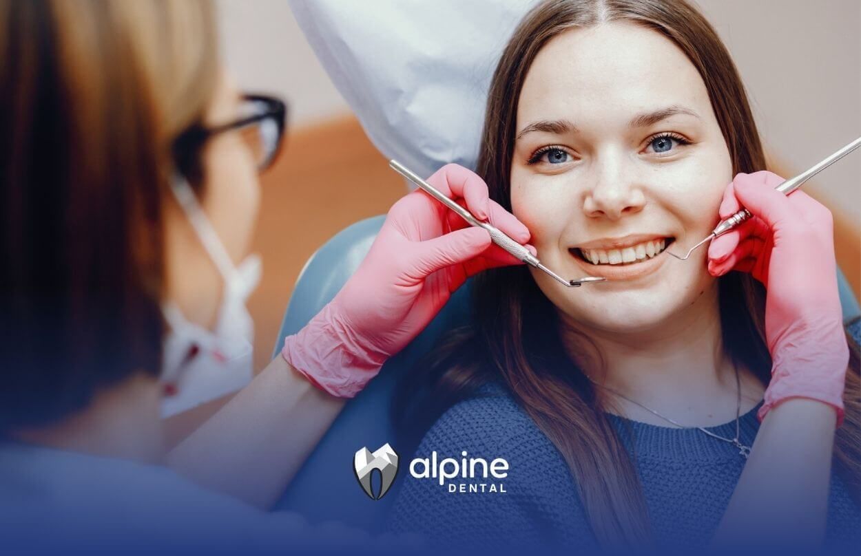 Dentist examining young woman’s teeth with. dental tools.