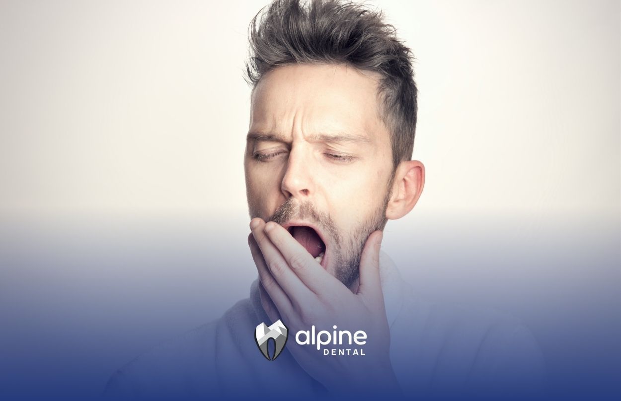A man is holding his cheek and covering his mouth with his hand as he experience severe toothache.
