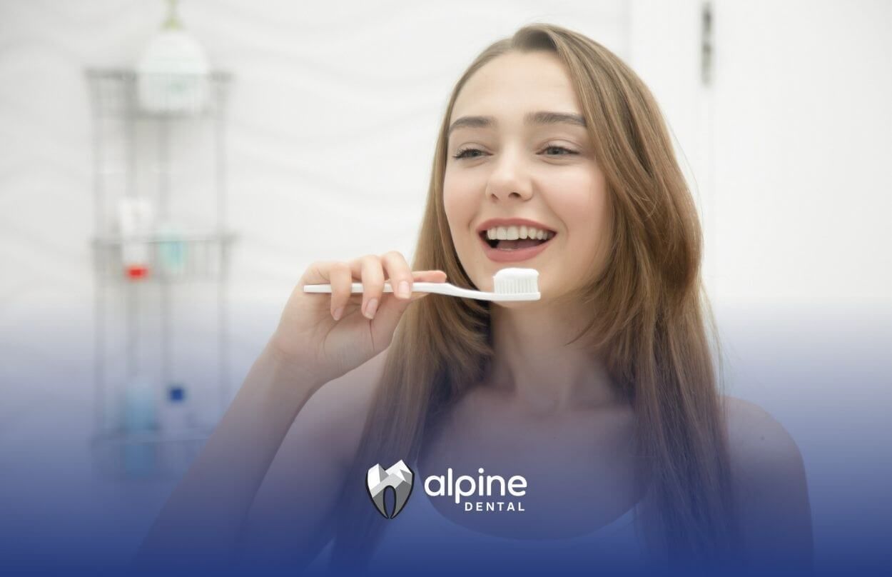 Young woman brushing her teeth and smiling.
