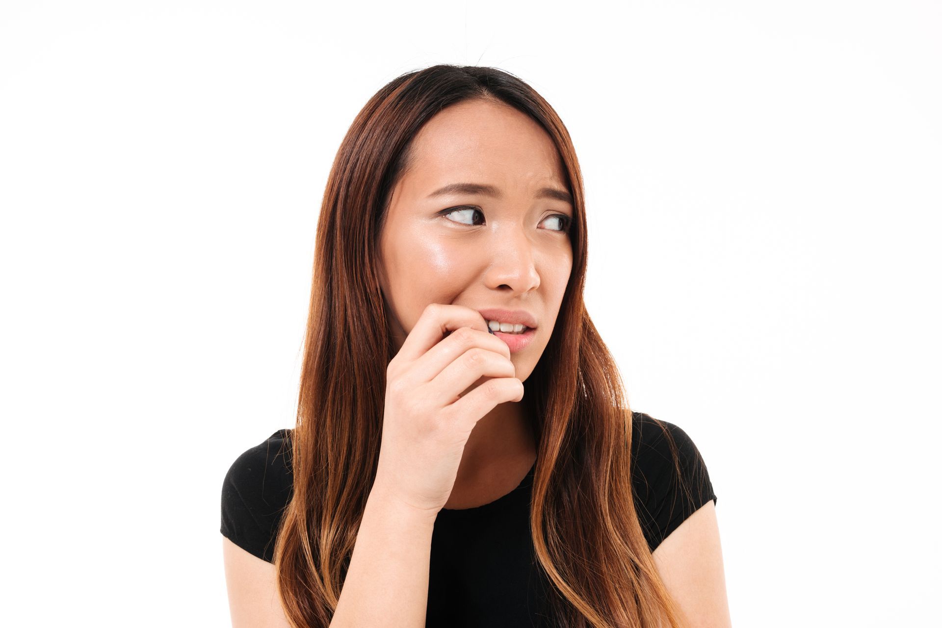 Woman with long brown hair biting fingernail, looking anxious. White background.