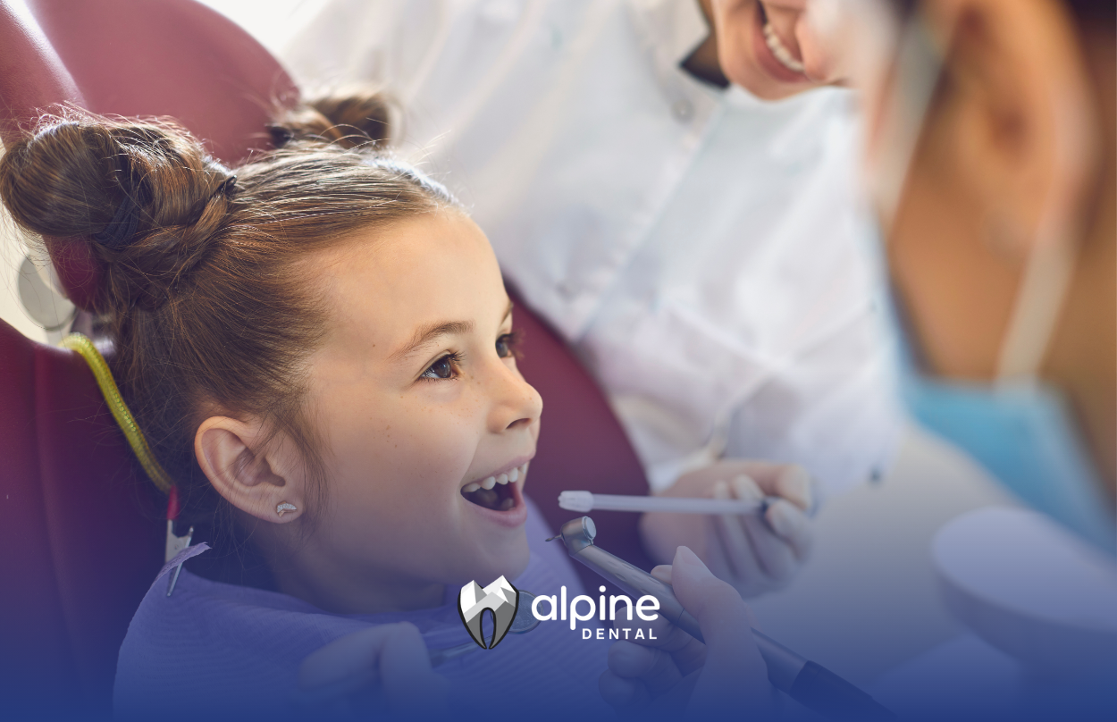 A young girl at a dentist's office with mouth open, receiving a dental checkup.
