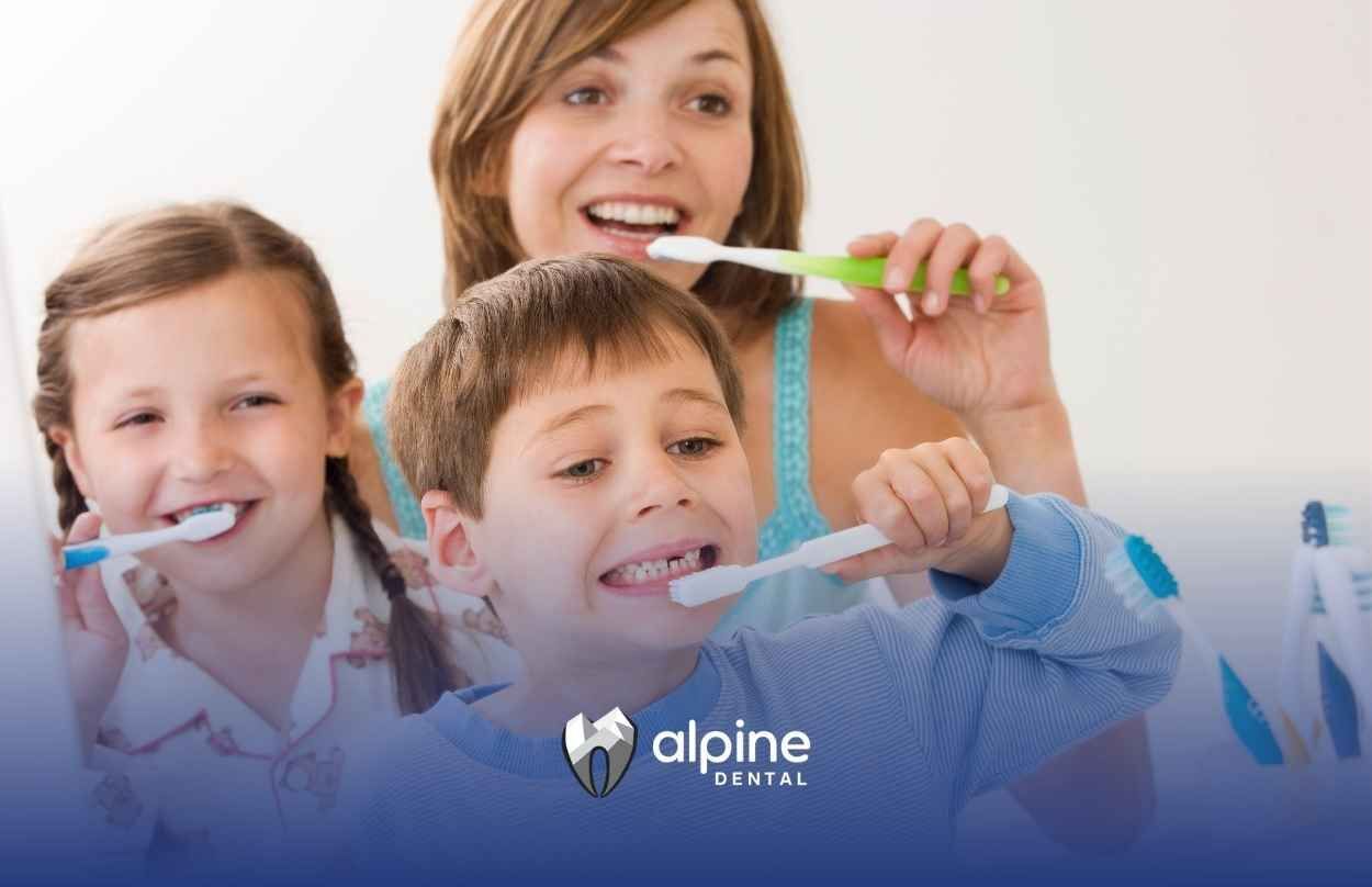 A woman and two children are brushing their teeth together.