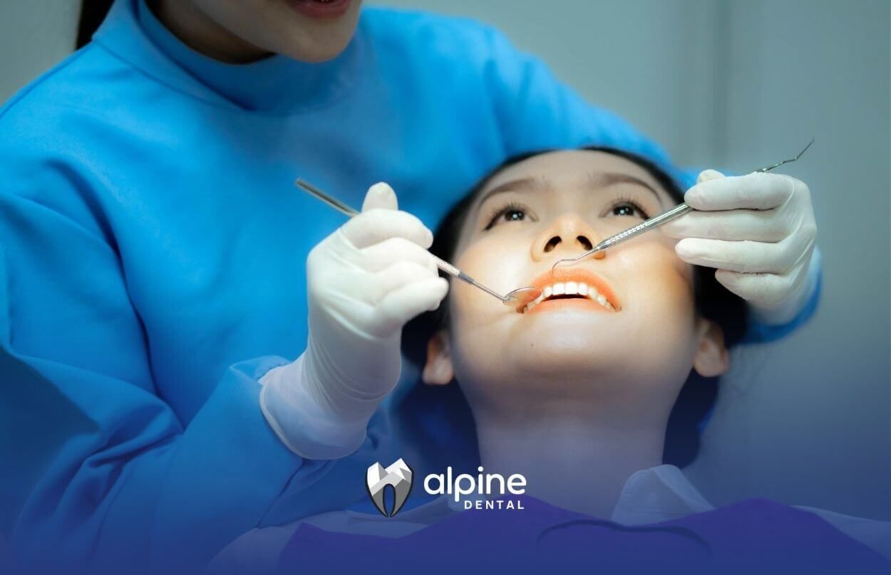 Dentist examining a patient’s teeth with dental tools.