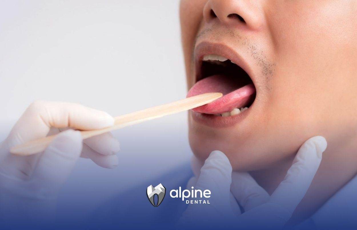 Dentist using tongue depressor to check mouth for any sign of oral disease at a dental clinic in NJ.