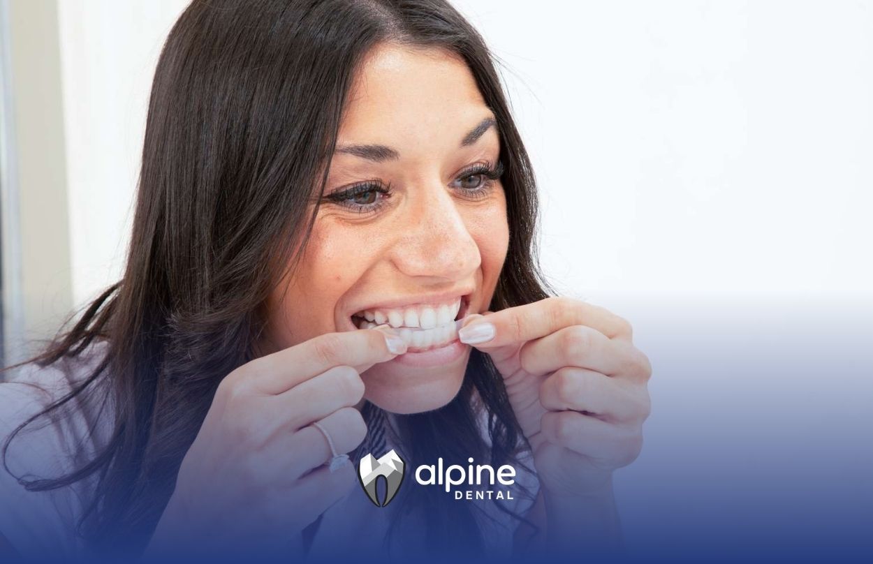 A woman placing whitening strips on her teeth after dental checkup in Lakewood, New Jersey.