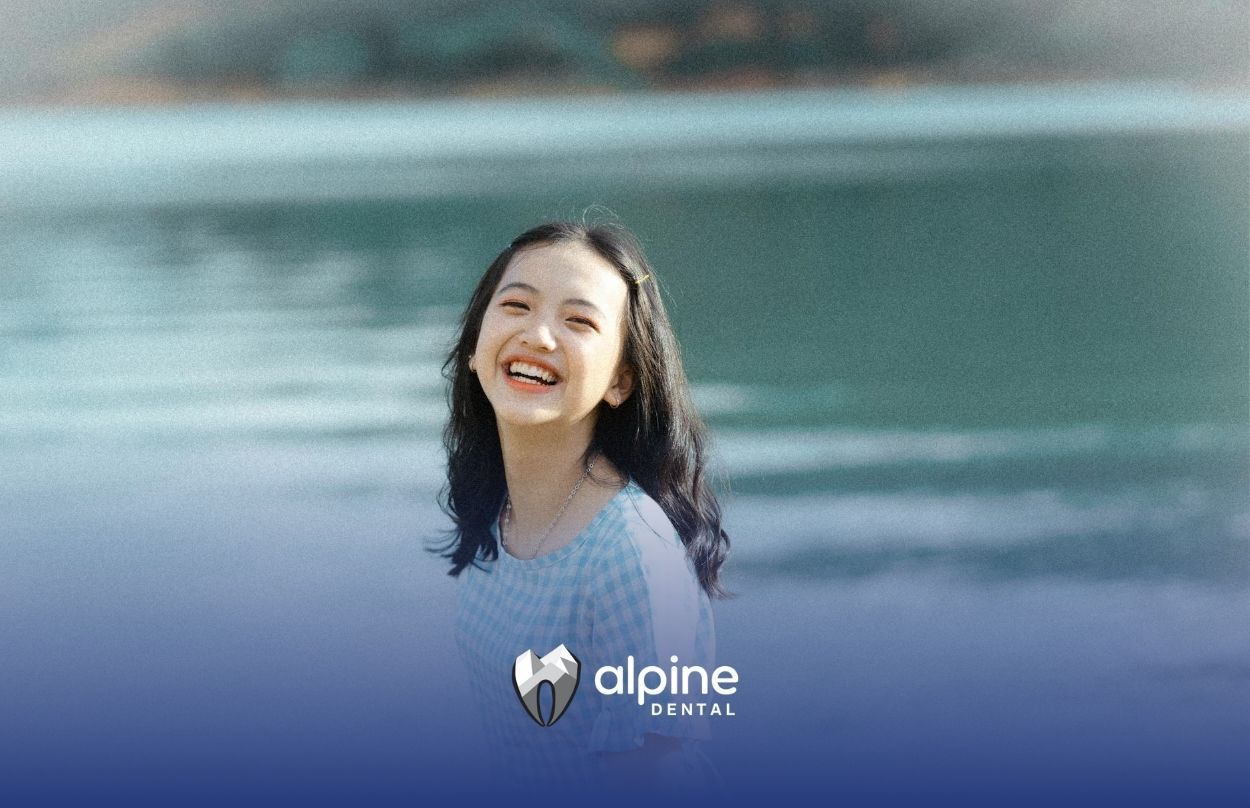 A young girl smiling brightly while standing outdoors by a stunning lake in Lakewood, New Jersey.