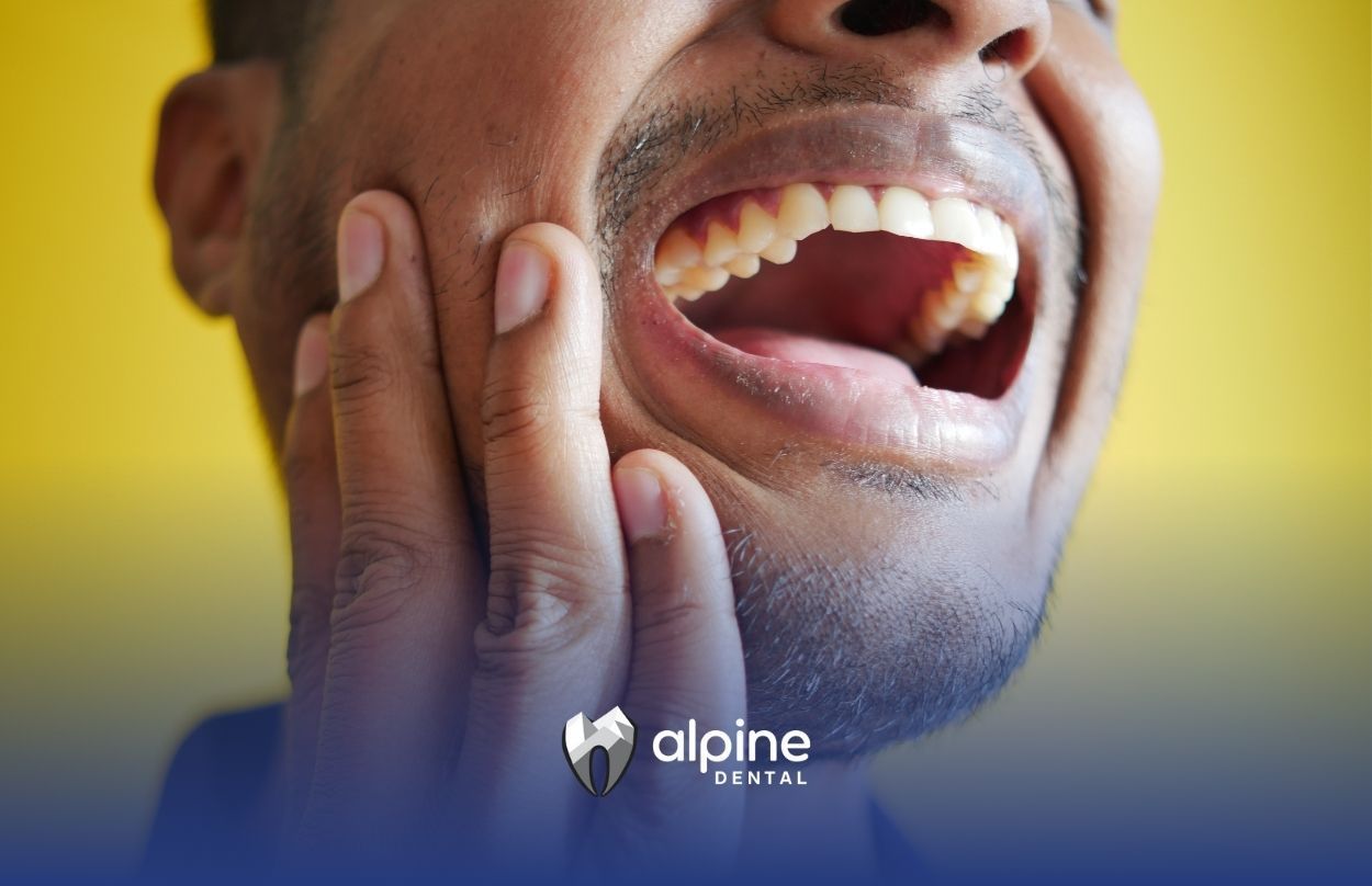 A man is holding his face in pain because he has a toothache.