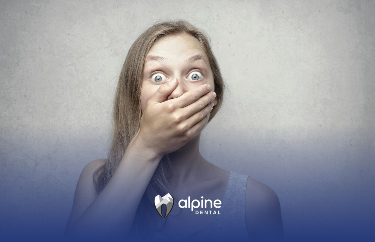 Surprised woman with contagious gum disease is covering mouth with hand after dental checkup in NJ.