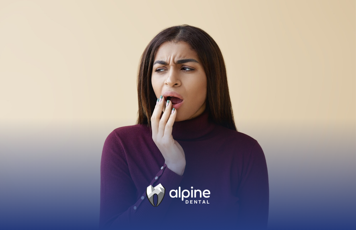 A woman is covering her mouth with her hand because she has a toothache.