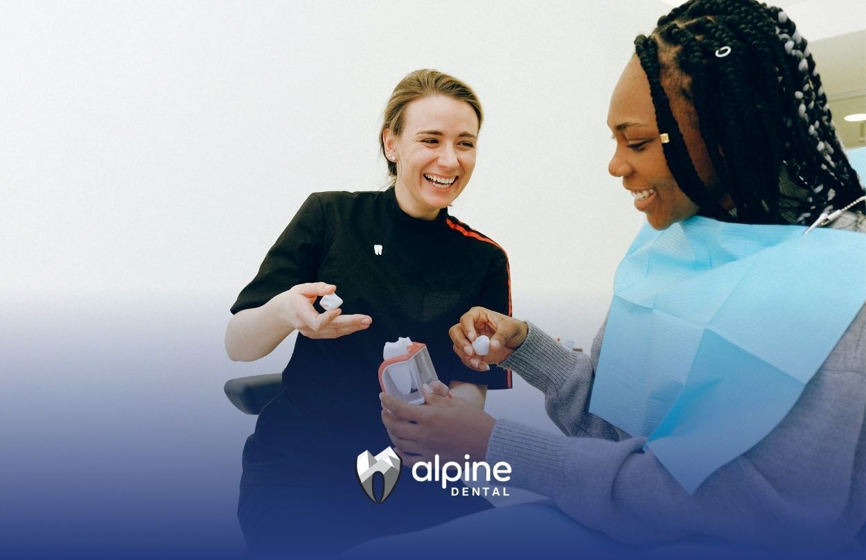 A dentist showing dental model to her smiling woman patient who regularly visits in Lakewood, NJ.