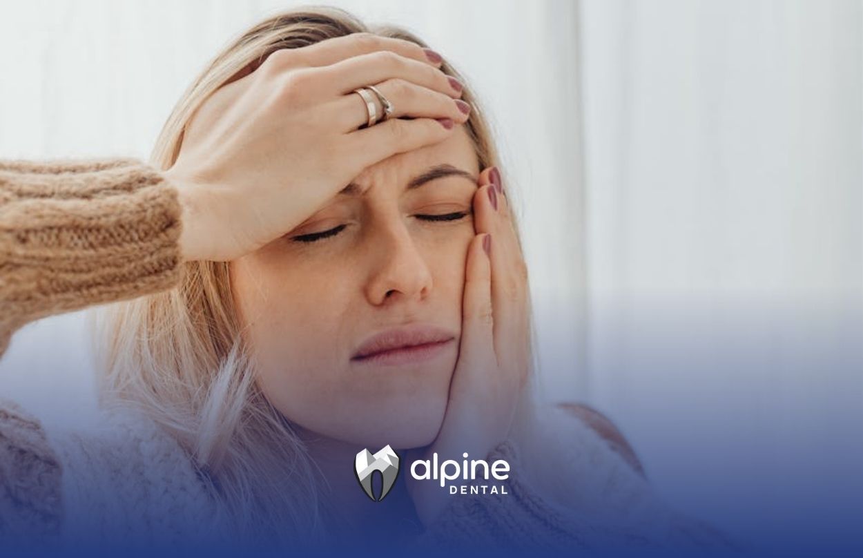 Woman with headache and swollen gums touching her face as she plans to go to a dental clinic in NJ.