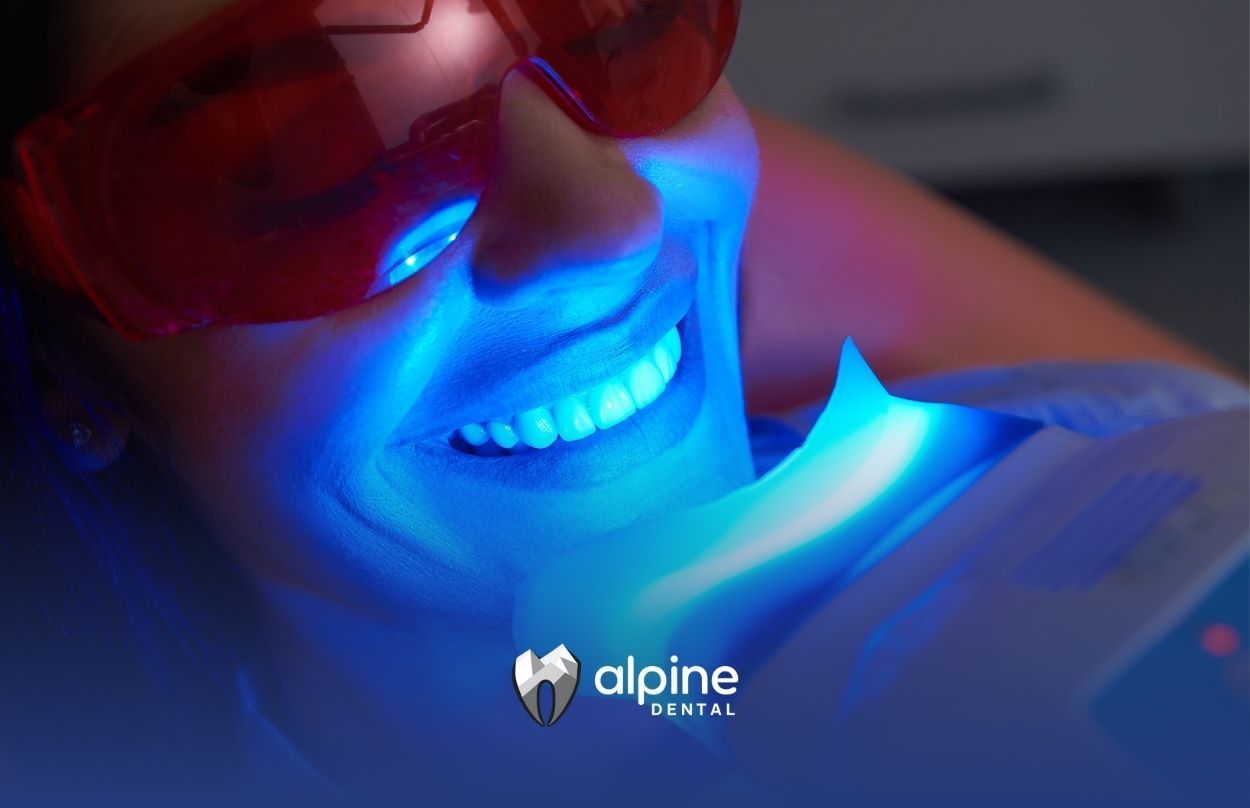 A woman is getting her teeth whitened with a blue light.