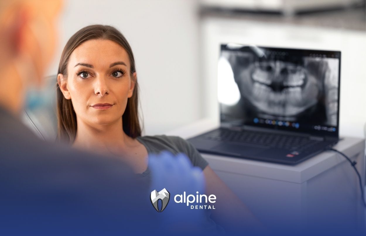 A woman is sitting in a dental chair in front of a laptop computer.