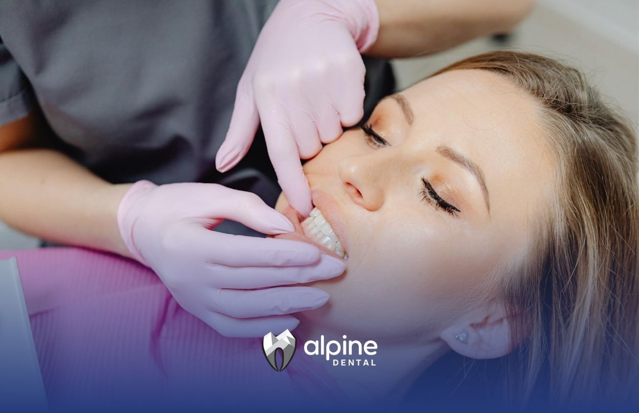 Dentist examining a woman patient's dry mouth with pink gloves during dental checkup in Lakewood, NJ