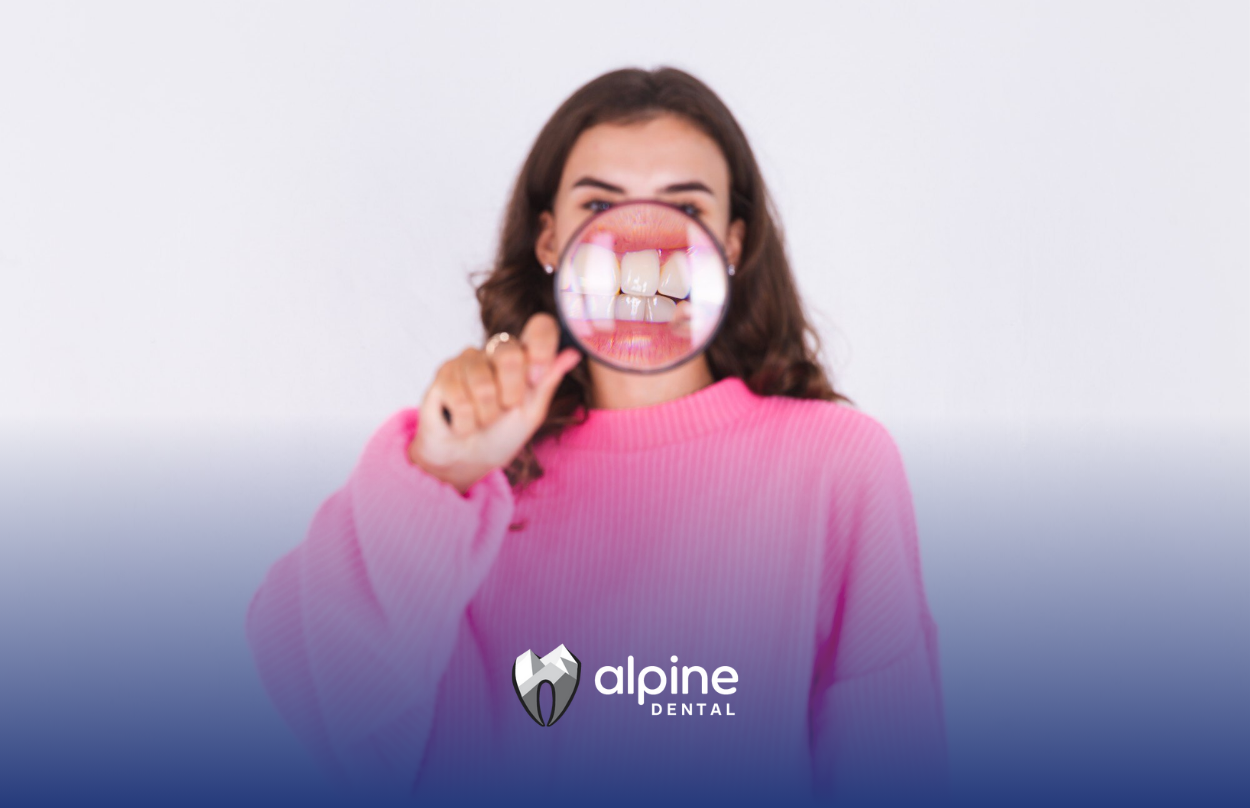 A woman is looking at her teeth through a magnifying glass.