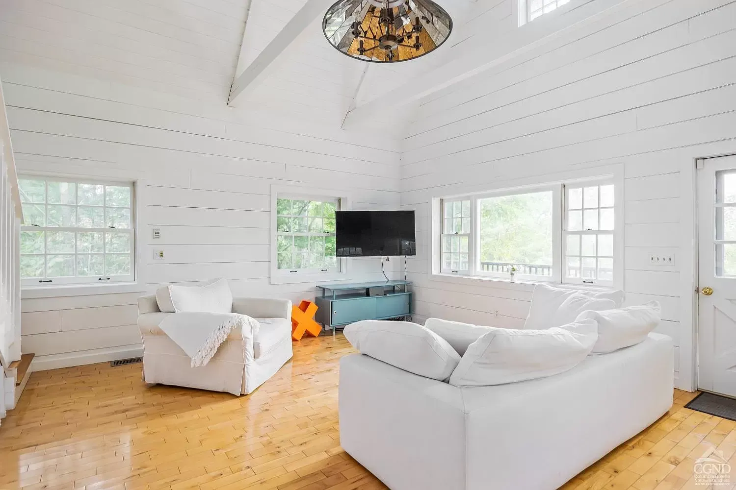 A living room with white furniture and a flat screen tv.
