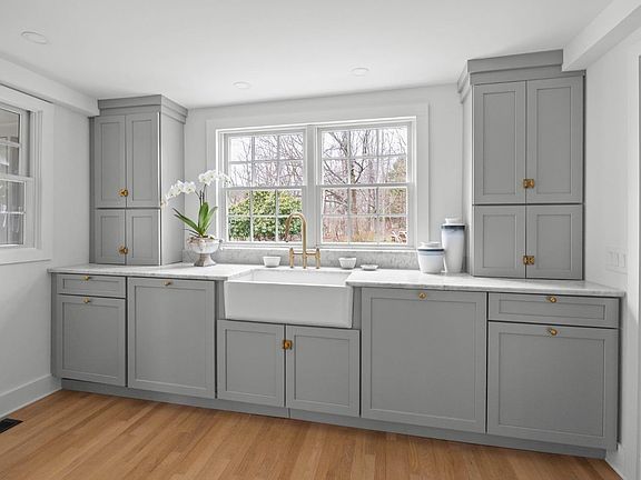A kitchen with gray cabinets and a white sink.