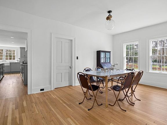 A dining room with a table and chairs and hardwood floors.