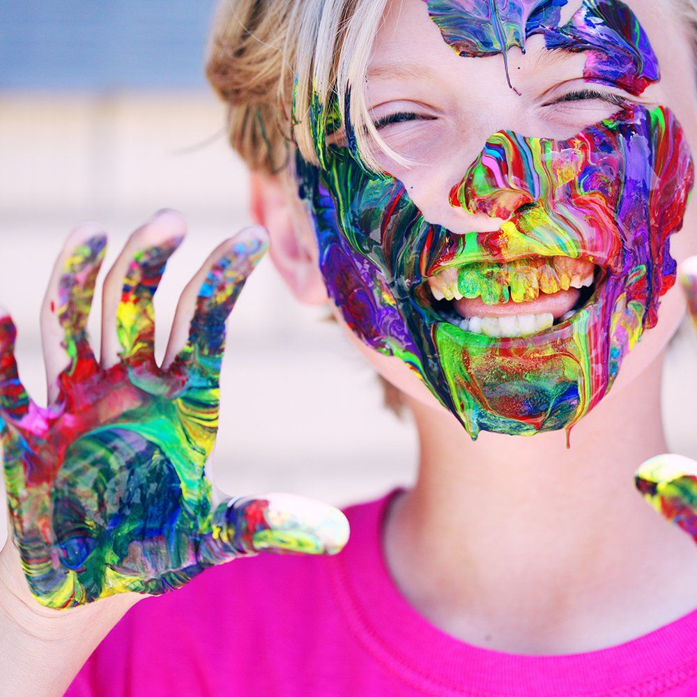 A young girl with paint on her face and hands