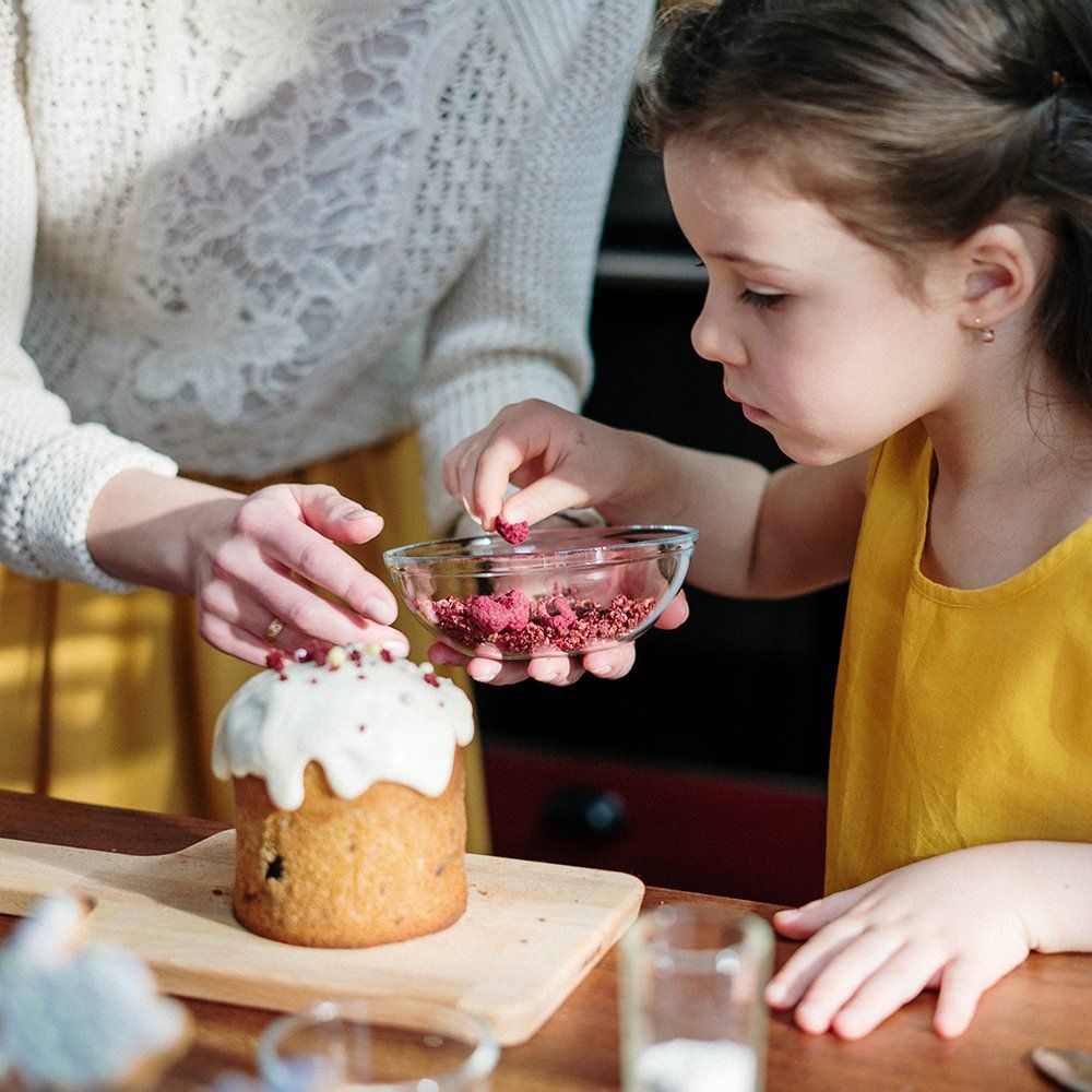A woman and a little girl are decorating a cake.