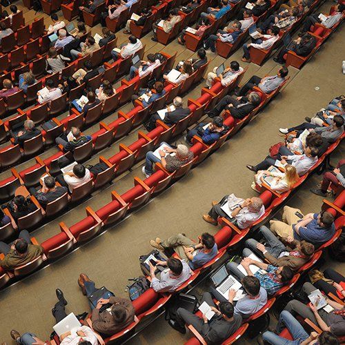 A large auditorium filled with people sitting in red seats