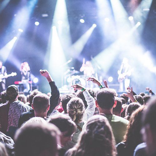 A crowd of people are watching a band on stage at a concert.