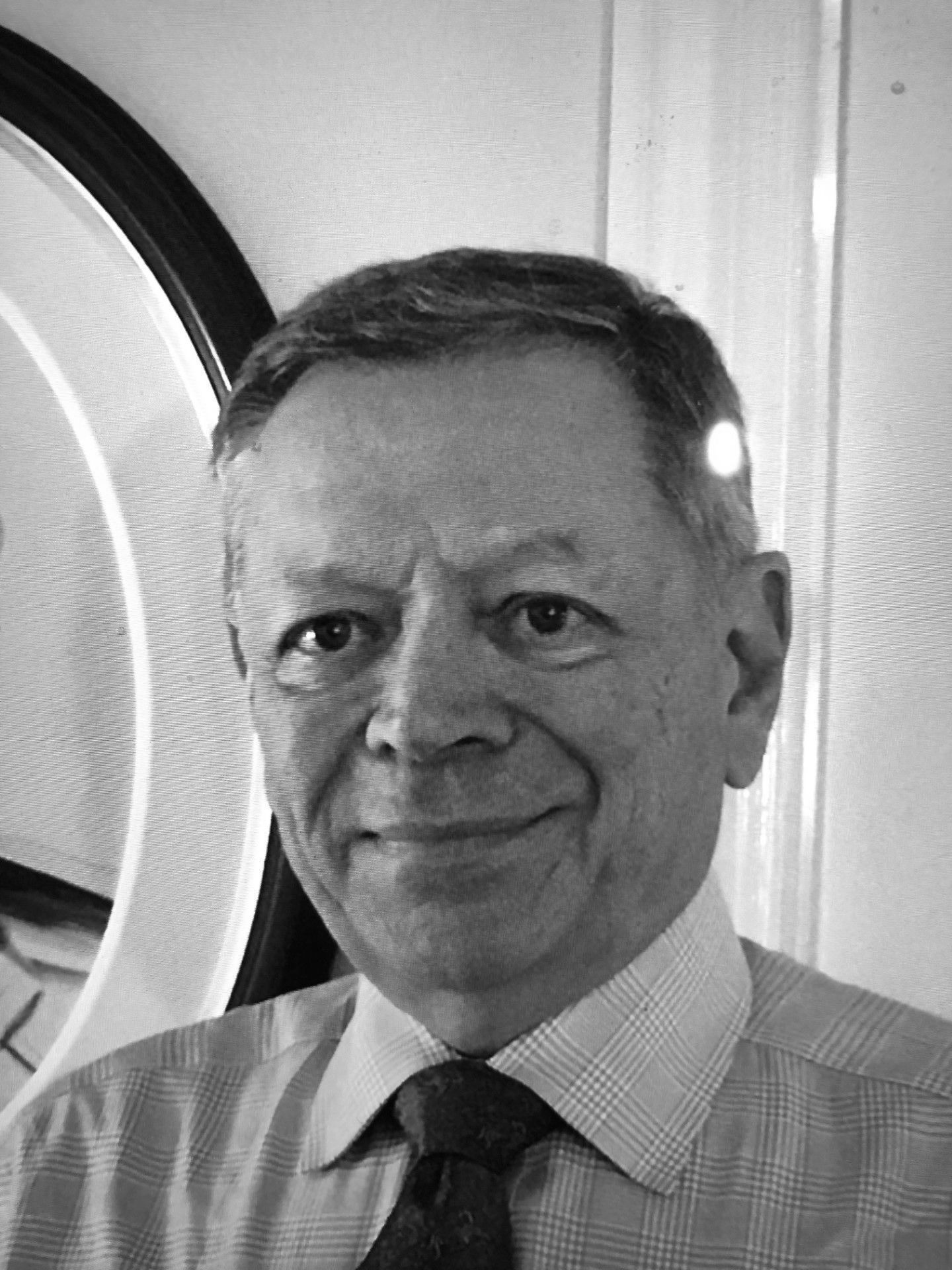 A man in a shirt and tie is smiling in front of a mirror.