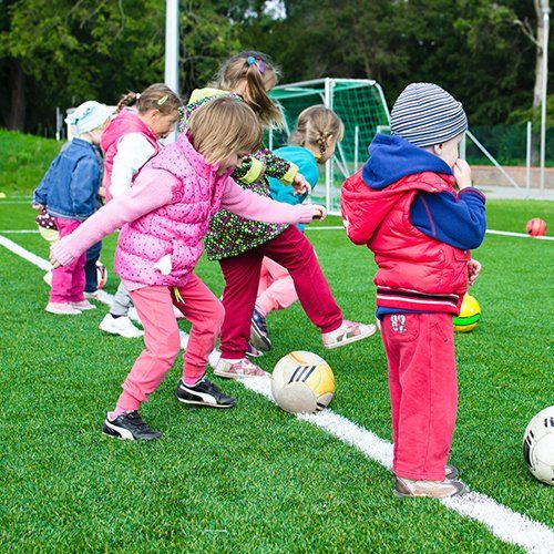 A group of children are playing with soccer balls on a field.