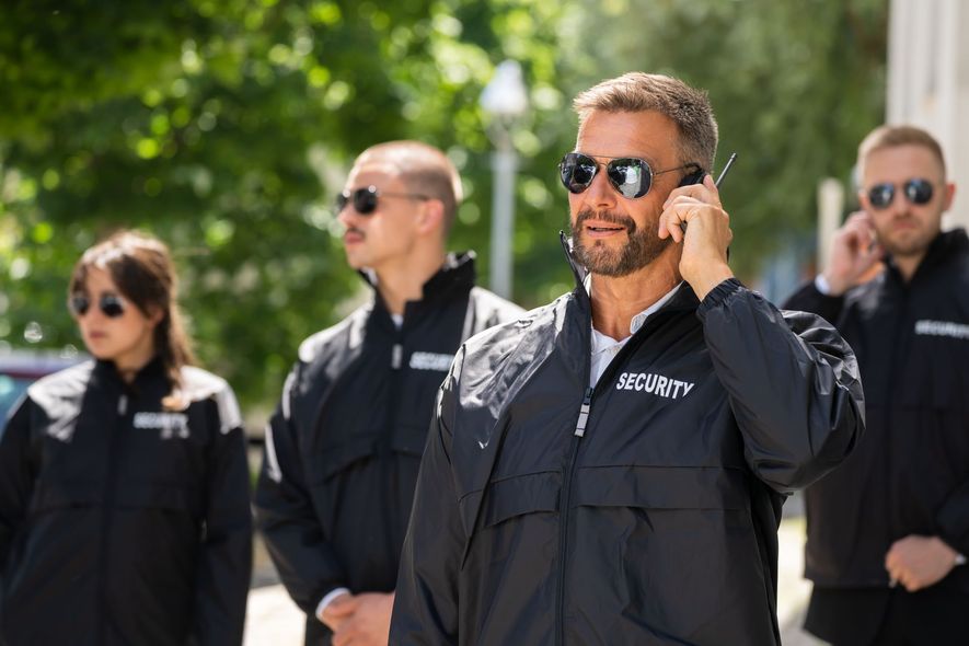 A man is talking on a walkie talkie while standing next to a group of security guards.