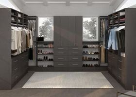 A walk in closet filled with lots of clothes and shoes.