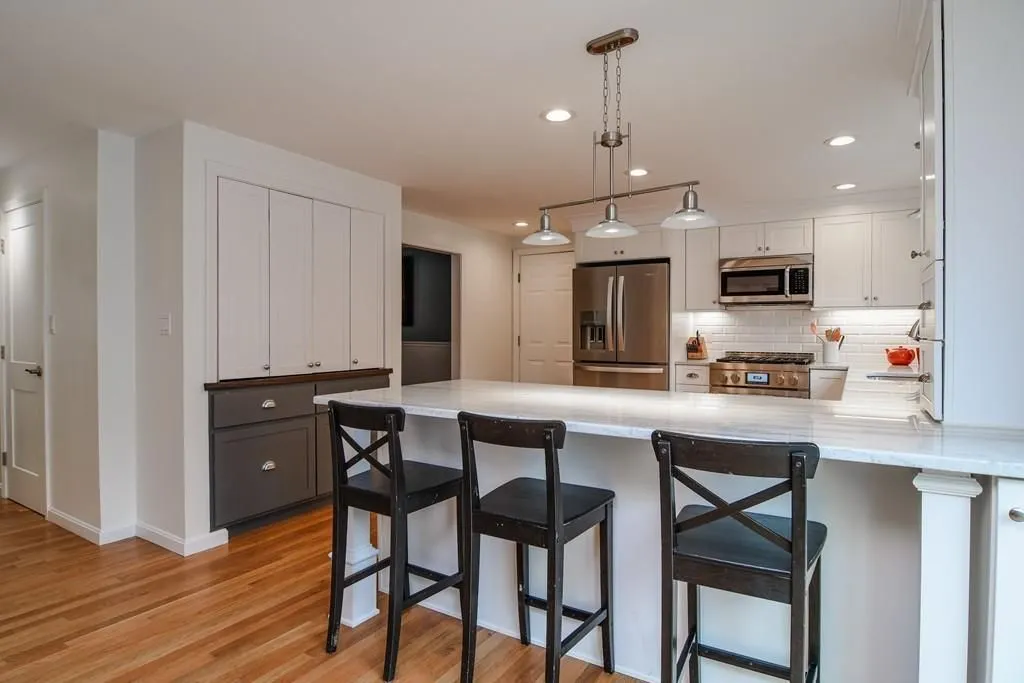 A kitchen with a large island and three bar stools.