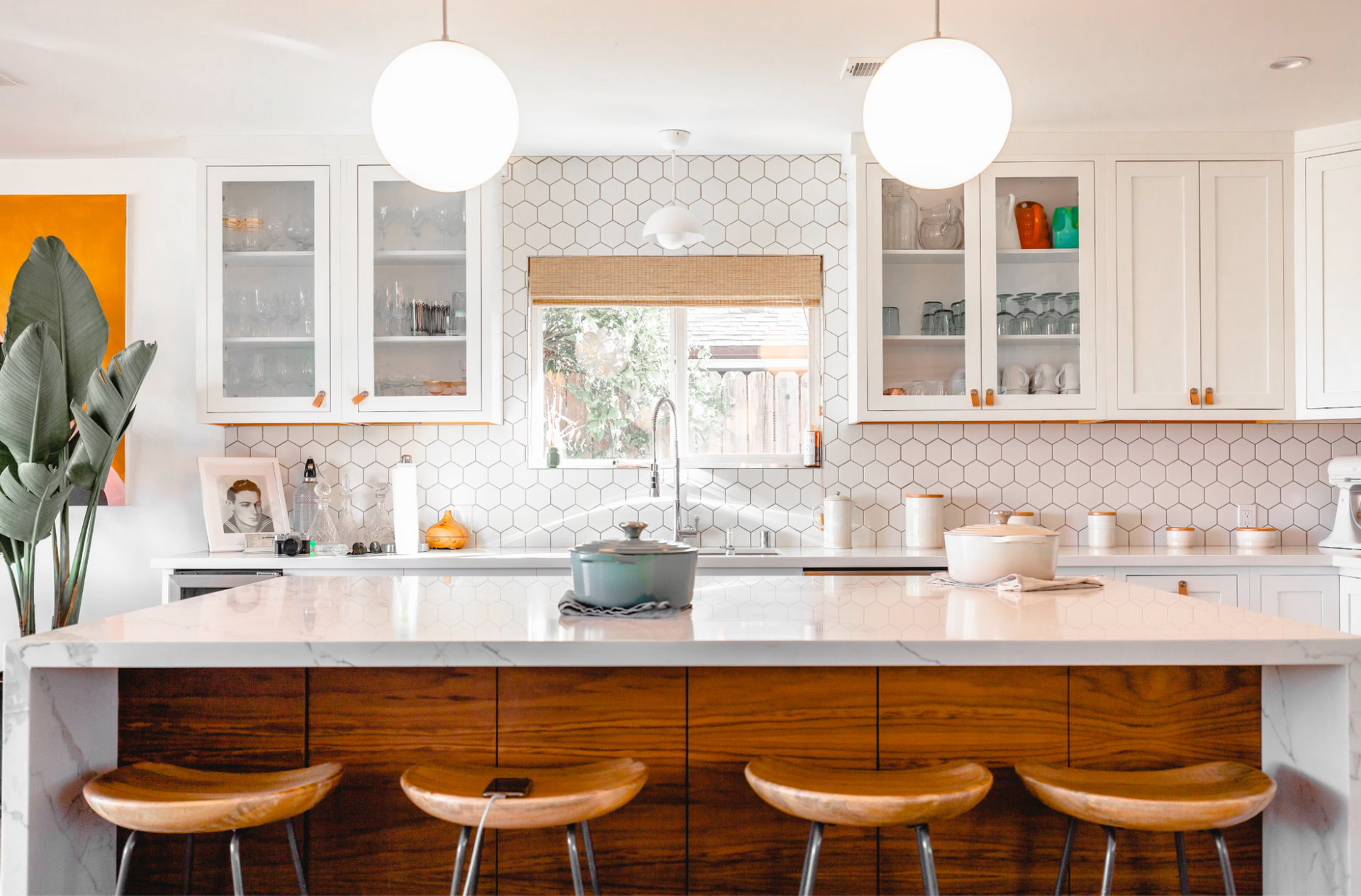 A kitchen with white cabinets and wooden stools and a large island.