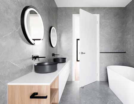 A bathroom with two sinks , two mirrors and a bathtub.