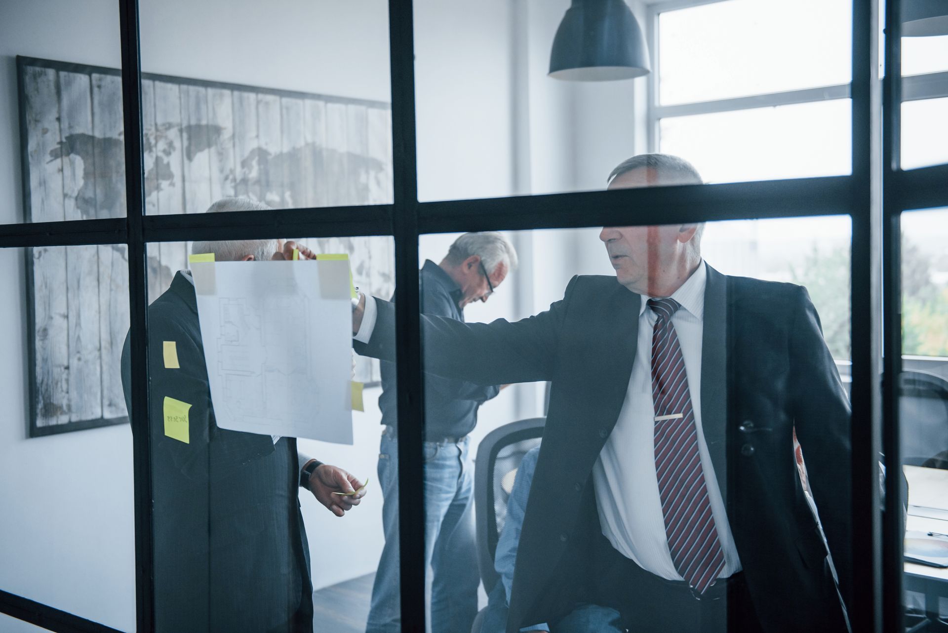 A man in a suit and tie is standing in front of a glass wall.