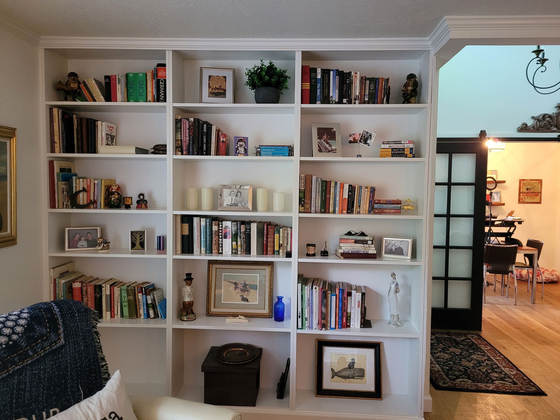 A living room with lots of books and pictures on the shelves
