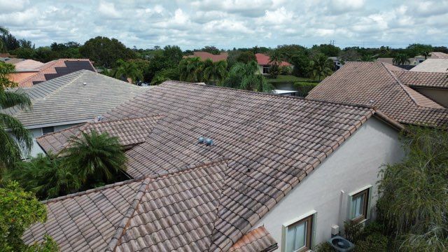 Roofs of houses with clay tiles under a cloudy sky in a residential area.