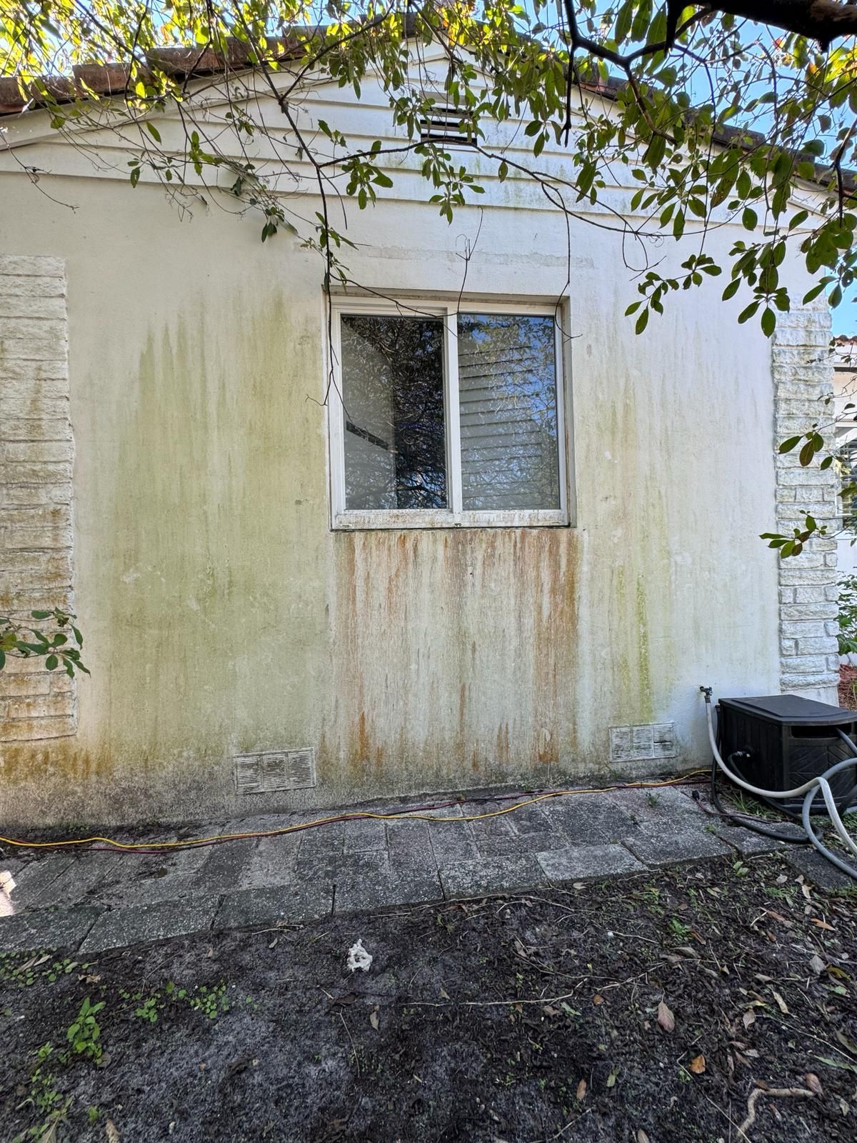 Exterior wall with window showing mildew and water stains.