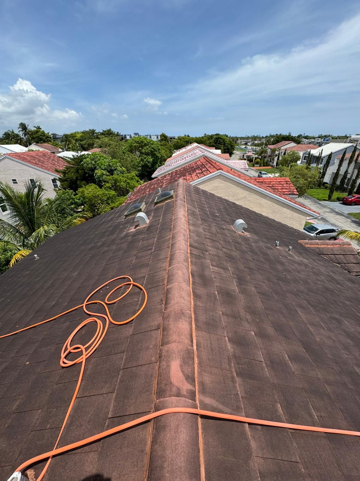 Brown rooftop with orange rope, overlooking suburban houses and trees on a sunny day.