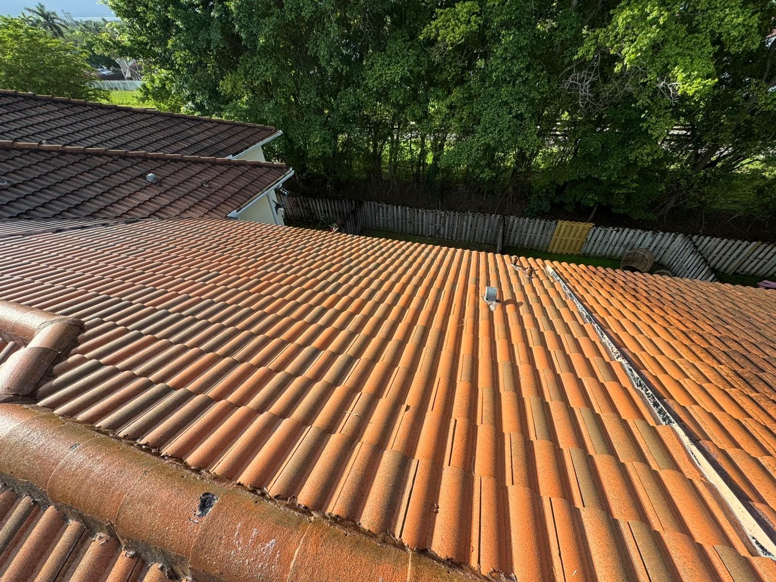 Brown terracotta tile roof with visible texture, trees in background.