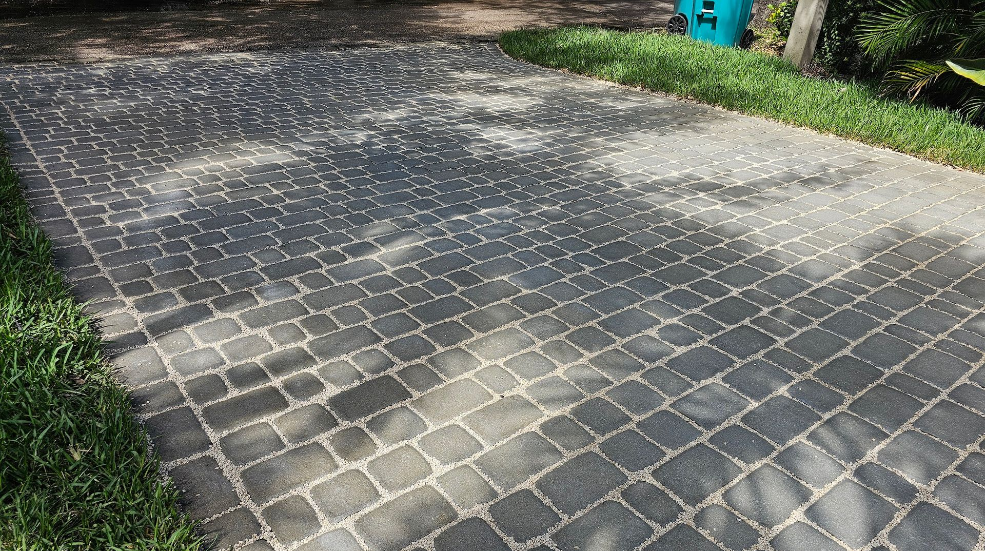 Cobblestone driveway with grass borders; sunny day.