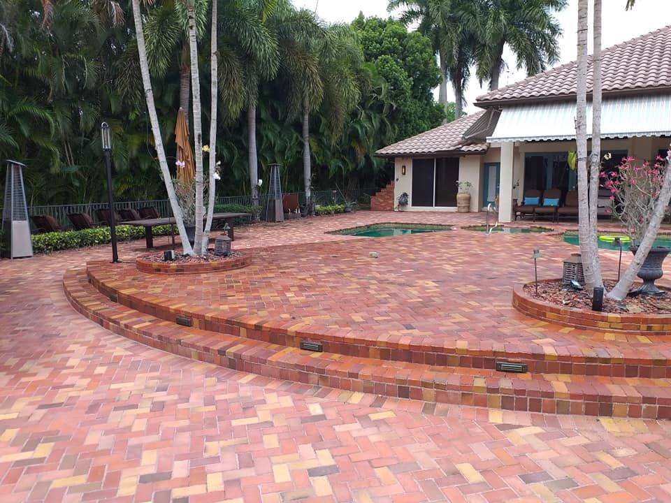 Driveway paved with square stones leading to a house with a car parked in front.