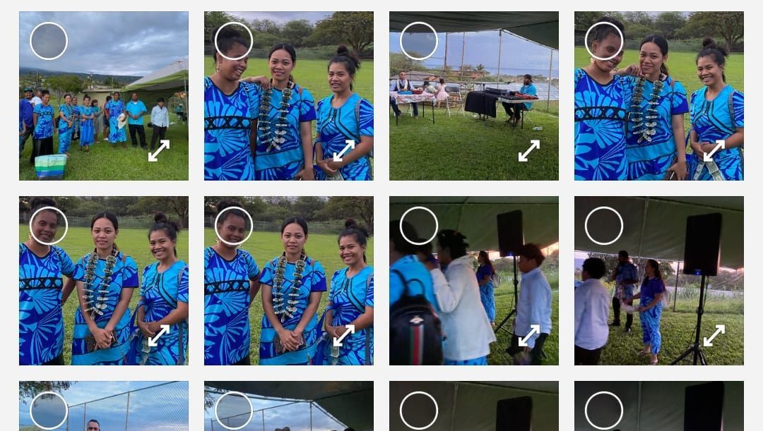 Group of people in blue attire with flower leis at an outdoor event.