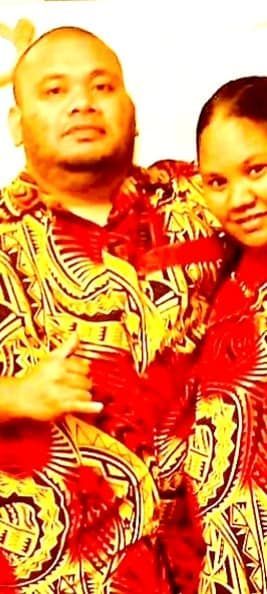 A man and a woman in matching patterned red and yellow shirts, possibly in a tropical setting.
