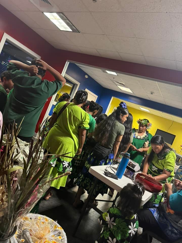 Group of people in green and blue outfits in a room, likely at an event.