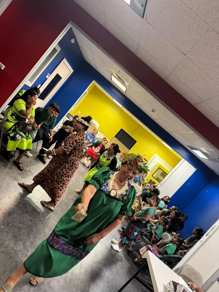 People in colorful outfits, some with flower crowns, in a room with blue, red, and yellow walls.