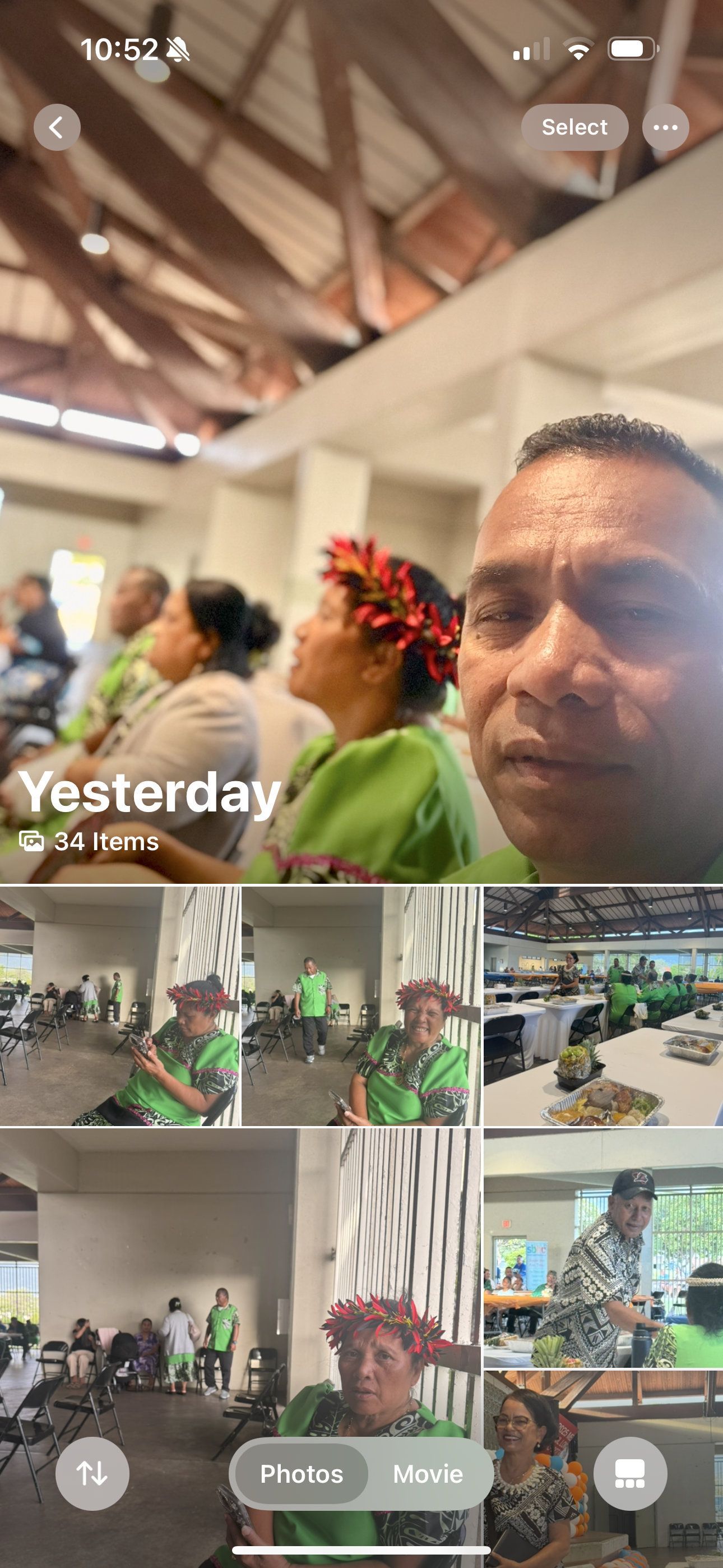 People in green outfits, a man taking a selfie, in a building with a wooden ceiling.