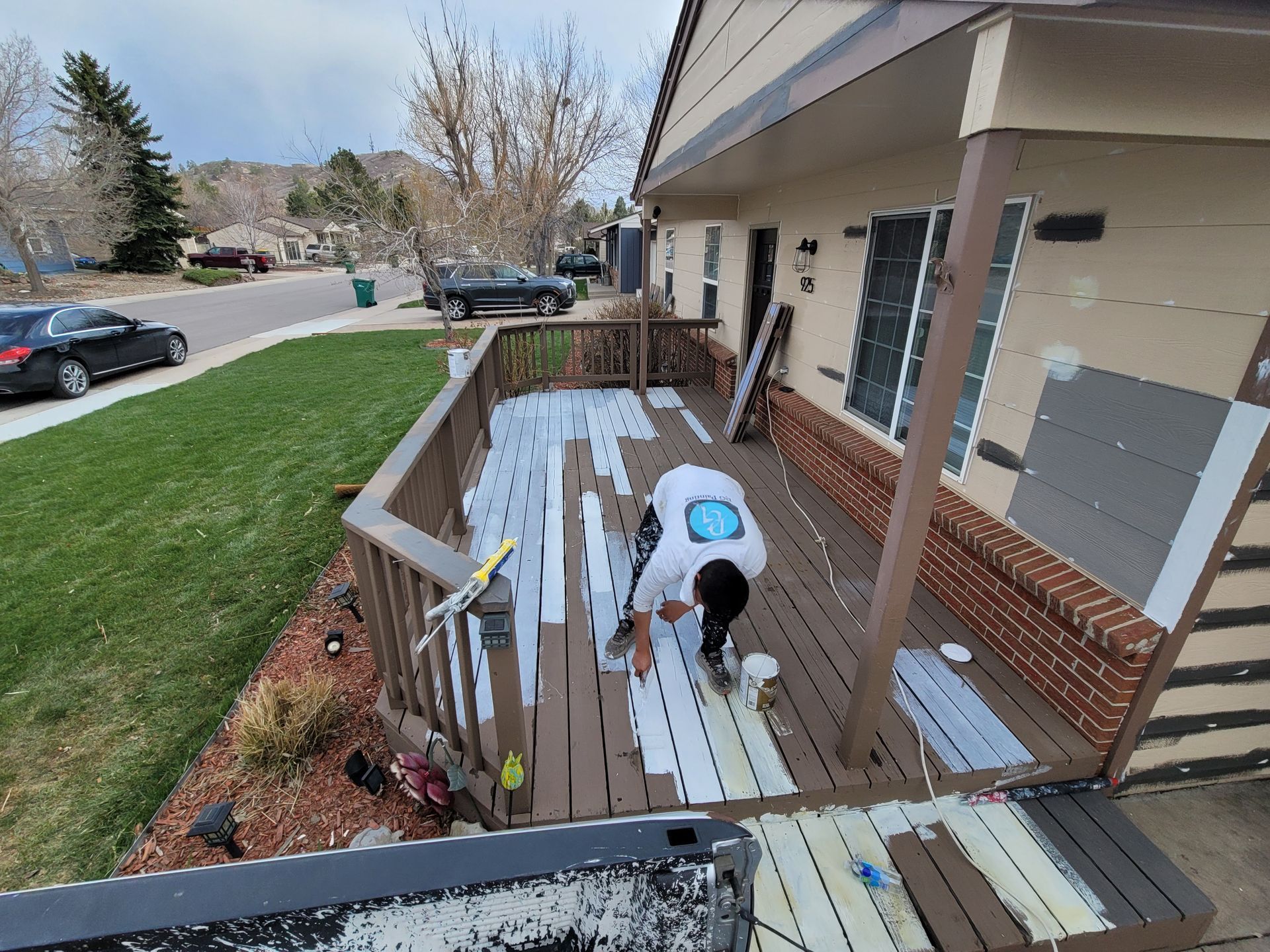 A man is painting a deck in front of a house.